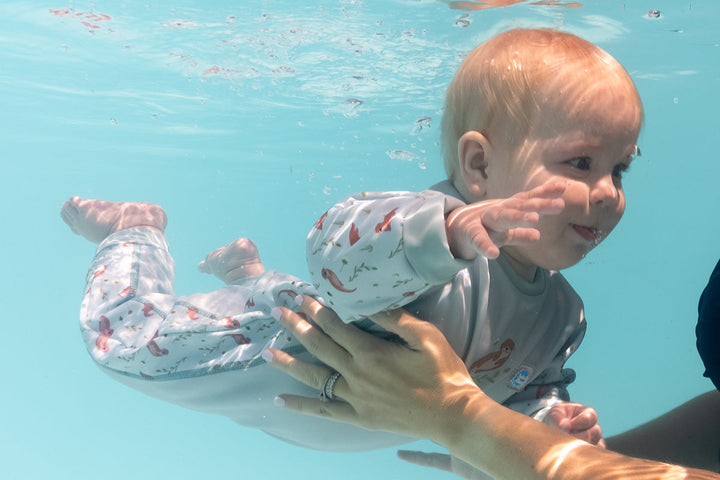 Child wearing otters themed baby wetsuit in light blue.