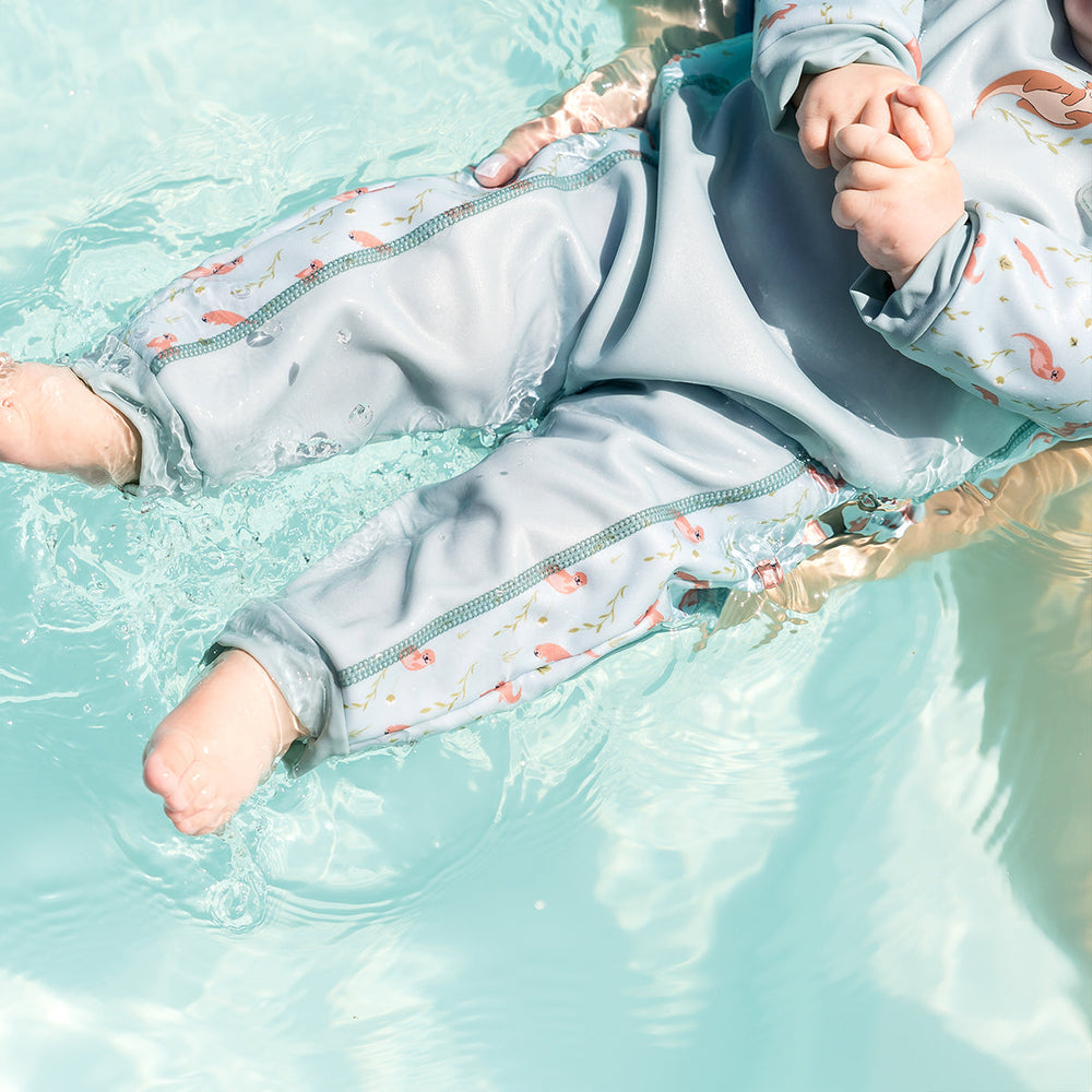 Child wearing otters themed baby wetsuit in light blue.