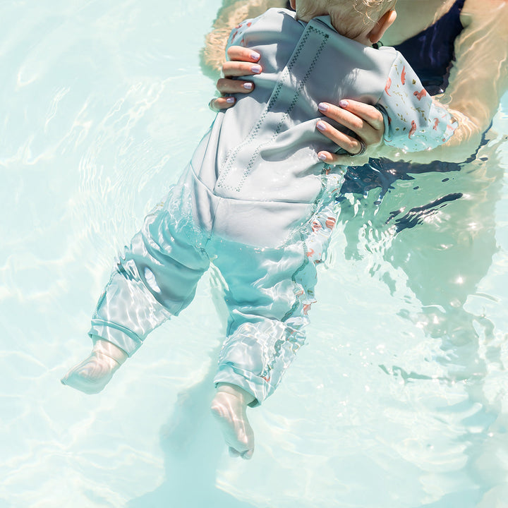 Child wearing otters themed baby wetsuit in light blue.