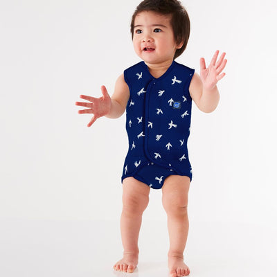 Lifestyle image of toddler wearing a Baby Wrap wetsuit in navy blue with white doves themed print.