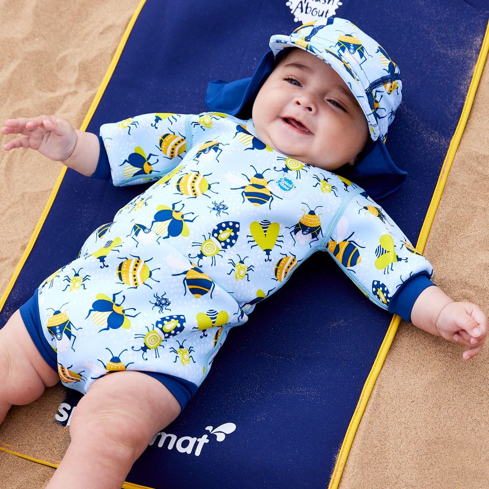 Lifestyle image of toddler wearing a legionnaire style sun hat in the beach. The hat is light blue and navy blue, with insects themed print panel. He's also wearing matching Happy Nappy wetsuit.