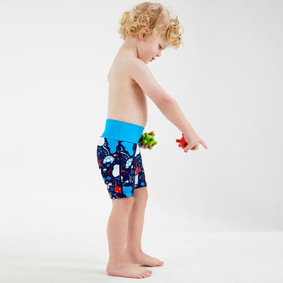 Lifestyle image of toddler wearing neoprene swim shorts in navy blue with blue waist and under the sea themed print, including octopus, turtles, fish, stingray and more.