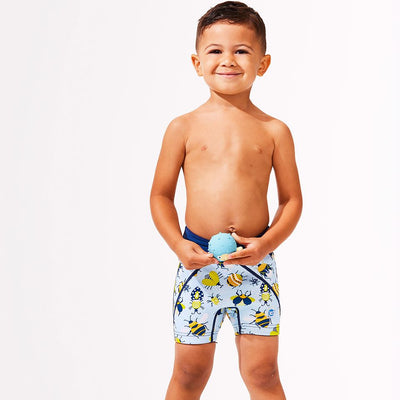 Lifestyle image of toddler wearing neoprene swim shorts in light blue with navy blue trims and insects print. Front.