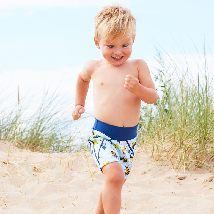 Lifestyle image of toddler wearing neoprene swim shorts in light blue with navy blue trims and insects print. 