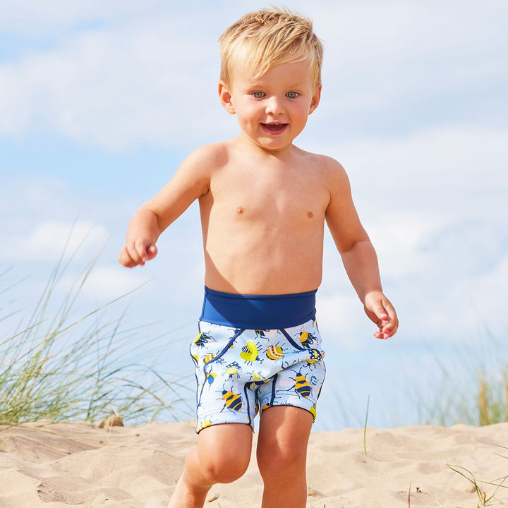 Lifestyle image of toddler wearing neoprene swim shorts in light blue with navy blue trims and insects print. 